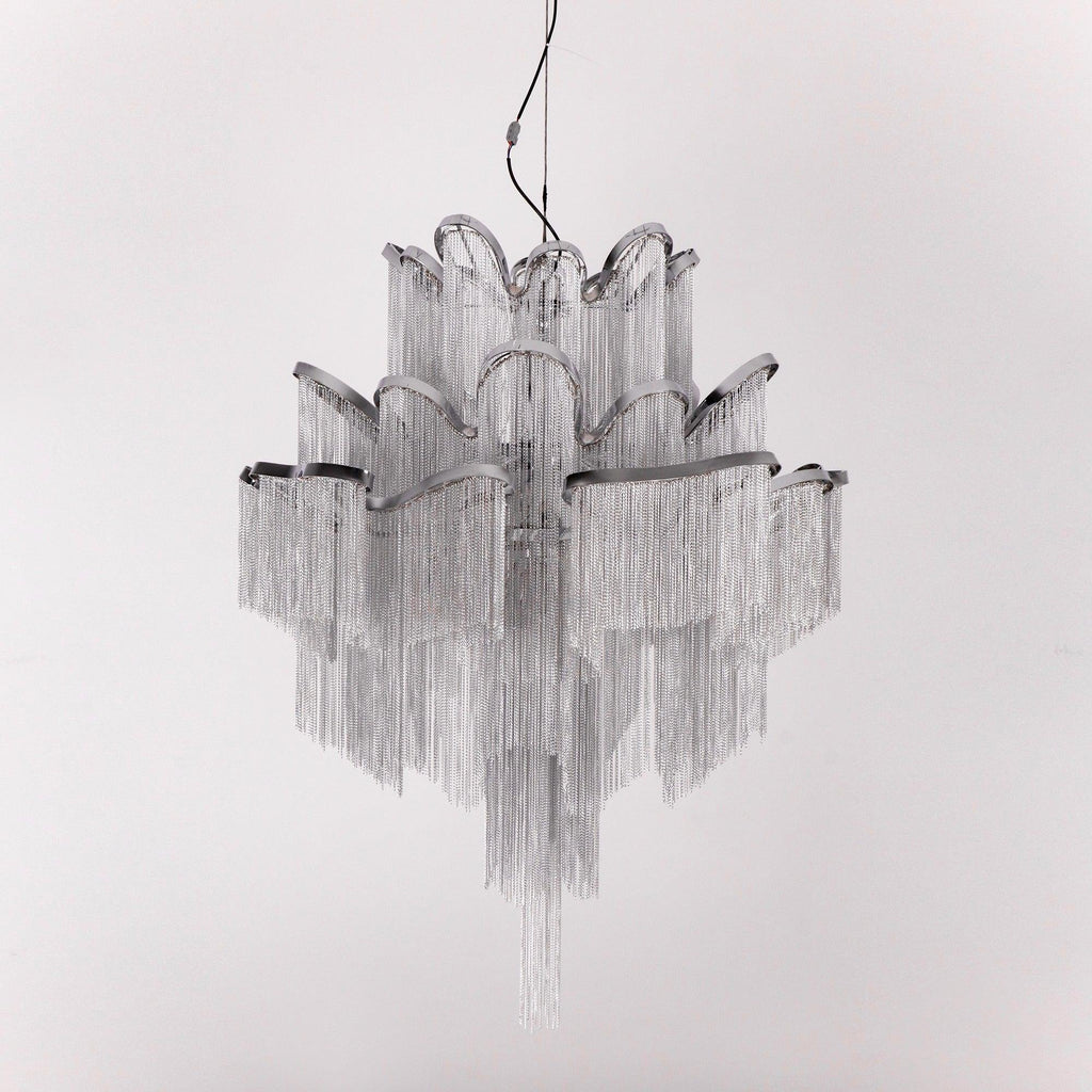 A silver Clérachic chandelier is shown unlit against a light grey backdrop, its chain tiers catching the light.