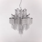 A silver Clérachic chandelier is shown unlit against a light grey backdrop, its chain tiers catching the light.
