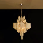 Warm and softly lit, this gold Clérachic chandelier glows against a plain black backdrop.