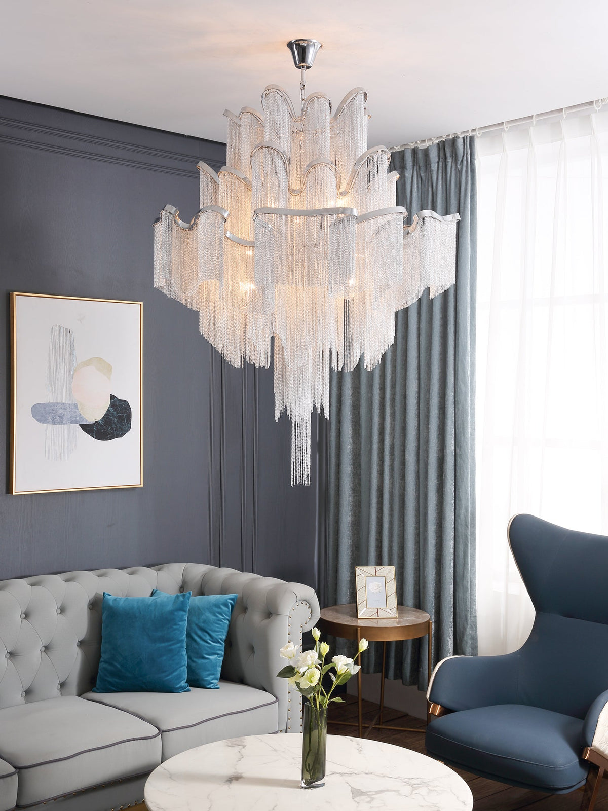 From a lower angle in the same grey-sofa living room, this lit silver Clérachic chandelier fills the ceiling space.