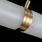 Close-up of the brushed brass collar where two alabaster tube sections meet along the lit bar.