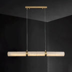 The Stream pendant lit against a black wall, its alabaster bar glowing warm from within.