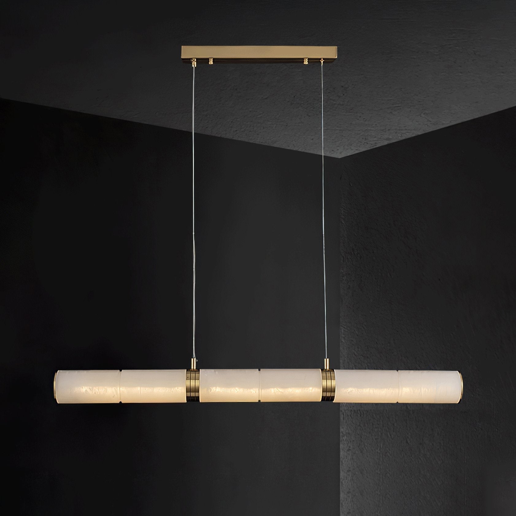 The Stream pendant lit against a black wall, its alabaster bar glowing warm from within.