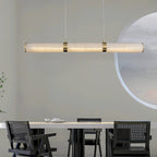 The pendant lit over a white dining table in a pale room, with a large round artwork on the wall behind.