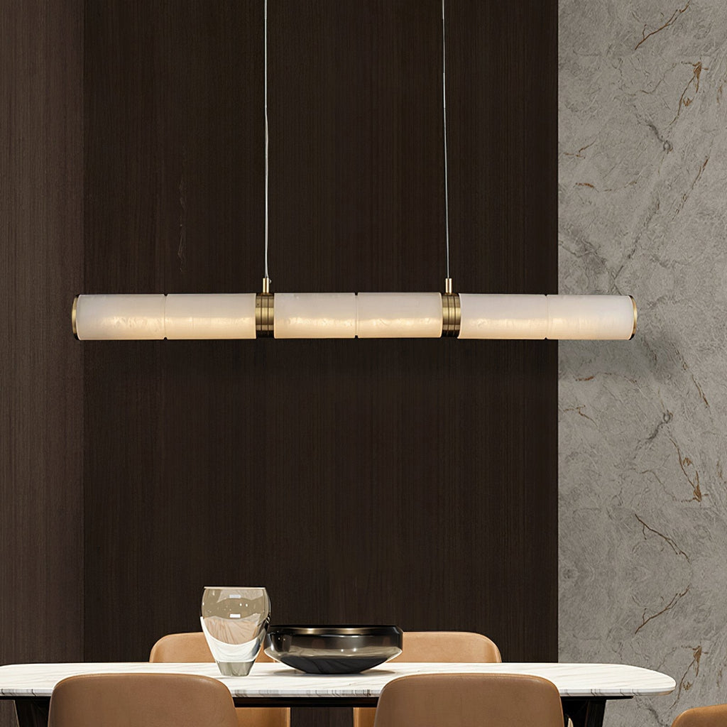The Stream pendant lit above a dining table, set against dark timber panelling and a veined marble wall.