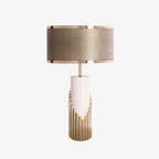 A second studio view of this Clérachic table lamp shows its fabric drum shade and gold stepped base against a plain backdrop.