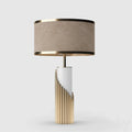 An alternate Clérachic finish shows a black-trimmed taupe shade over a white column and gold ribbed base, studio-lit.