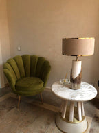 In a living-room corner, this Clérachic table lamp sits on a round white marble table beside an olive-green velvet chair.