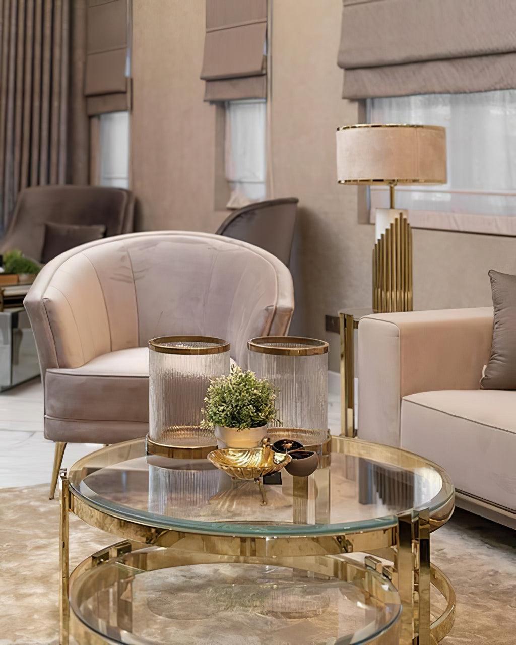 In a living room with blush armchairs and a glass coffee table, this Clérachic table lamp glows softly in the background.