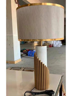 In an unstyled factory shot, this Clérachic lamp's gold stepped base sits on a bare floor with its cord coiled beside it.