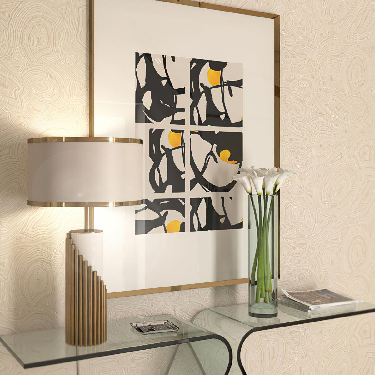 This Clérachic lamp sits on a glass console beside a black-and-white abstract print and a vase of white calla lilies.