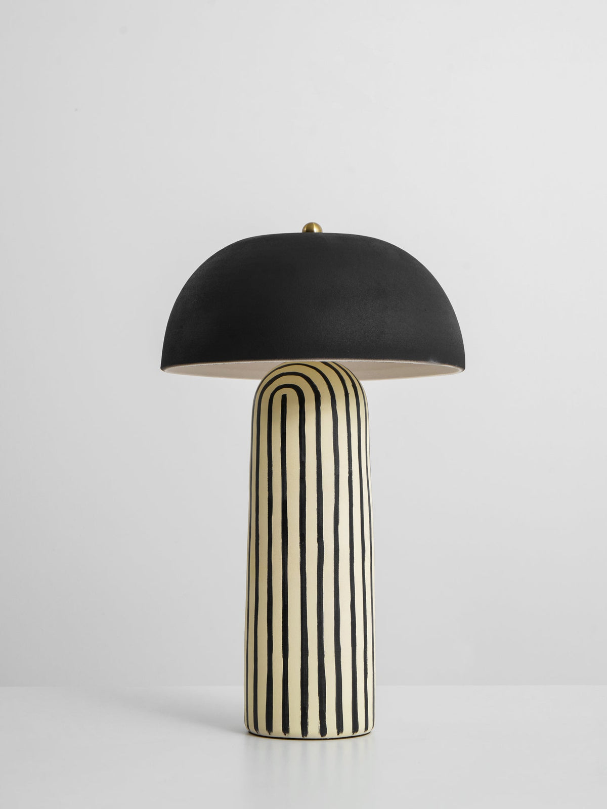 Photographed unlit on a plain light surface, this Clérachic table lamp's dome sits above the striped ceramic base.
