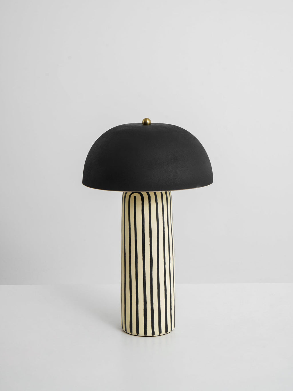 This Clérachic table lamp is shown on a plain white background, its matte black dome centred above the striped base.