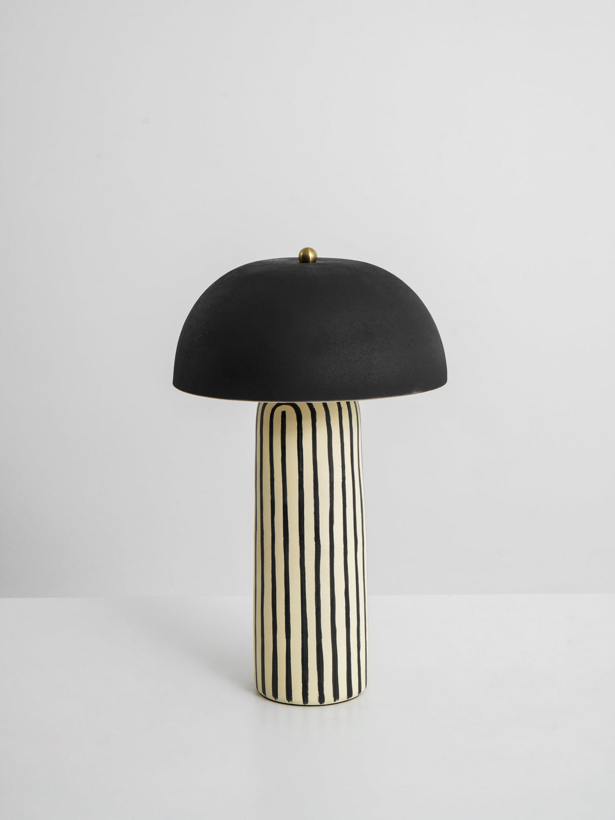 This Clérachic table lamp is shown on a plain white background, its matte black dome centred above the striped base.