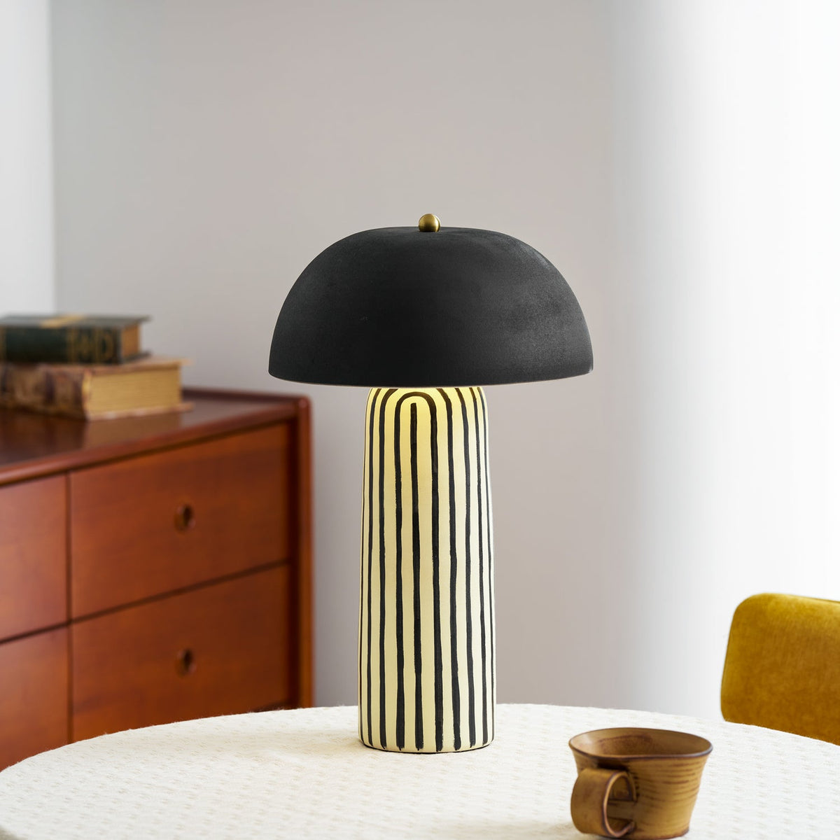 A wood dresser with brass handles sits behind this Clérachic table lamp, styled on a round table beside a small dark mug.