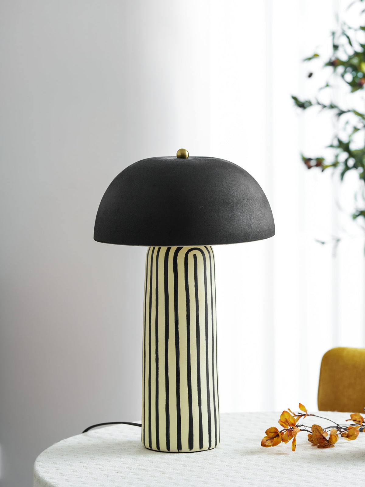 A sheer curtain and potted plant frame this Clérachic table lamp, styled on a round table by the window.