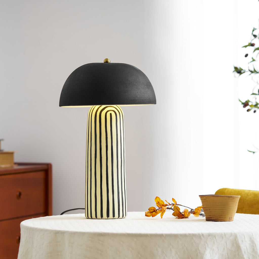 A low wood dresser and dried berries flank this Clérachic table lamp, styled on a round linen-covered table.