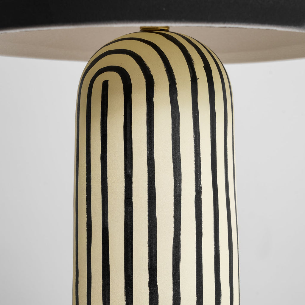 A close-up shows the striped ceramic base of this Clérachic table lamp curving up to meet the underside of the dome.