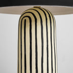 A close-up shows the striped ceramic base of this Clérachic table lamp curving up to meet the underside of the dome.