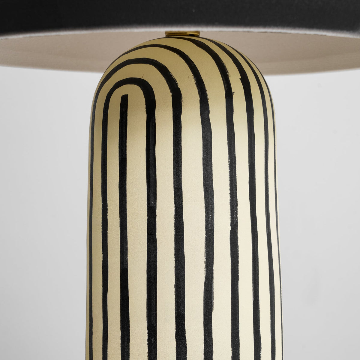 A close-up shows the striped ceramic base of this Clérachic table lamp curving up to meet the underside of the dome.