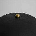 A close-up shows the brass finial atop this Clérachic table lamp's matte black dome shade.