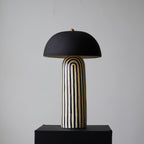 Turned to a three-quarter angle on its black plinth, this Clérachic table lamp shows the striped base beneath its dome shade.