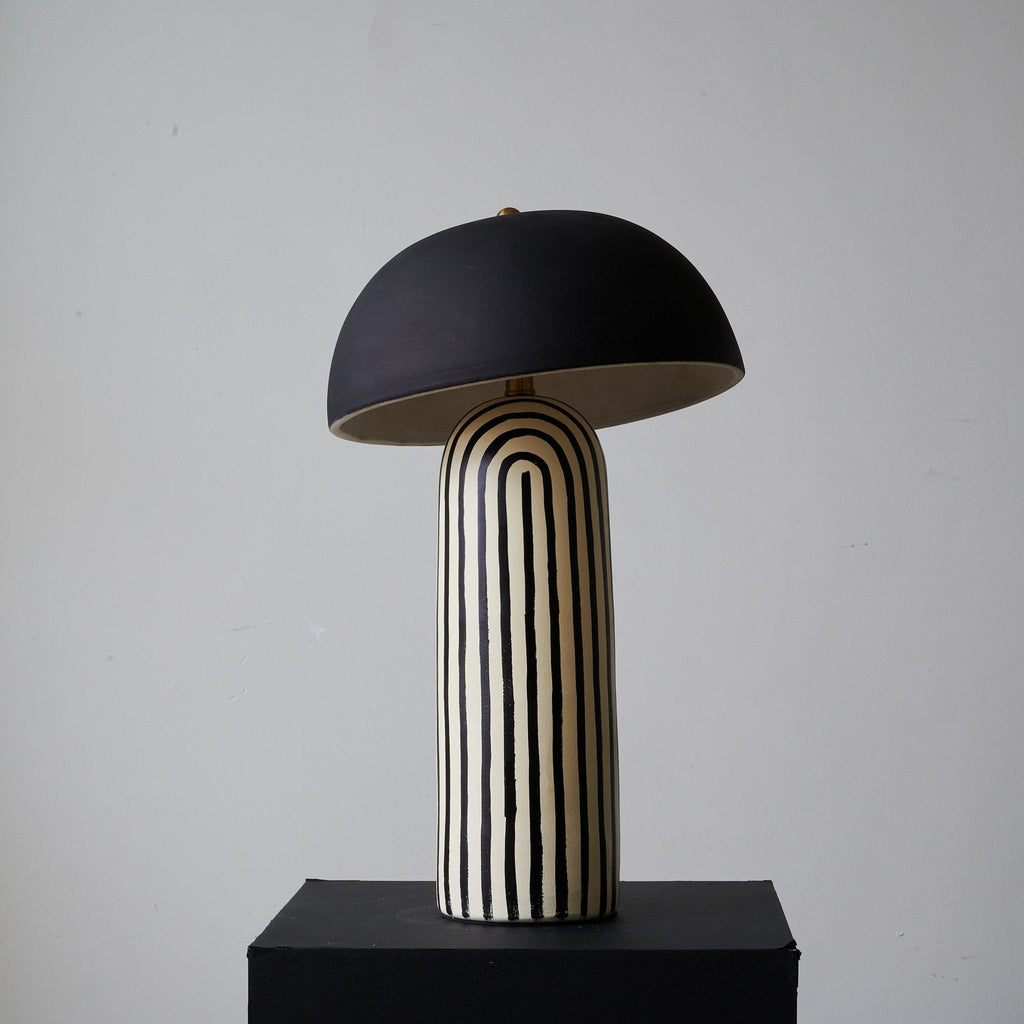 Centred on its black plinth, this Clérachic table lamp shows the dome shade above the vertically striped ceramic base.