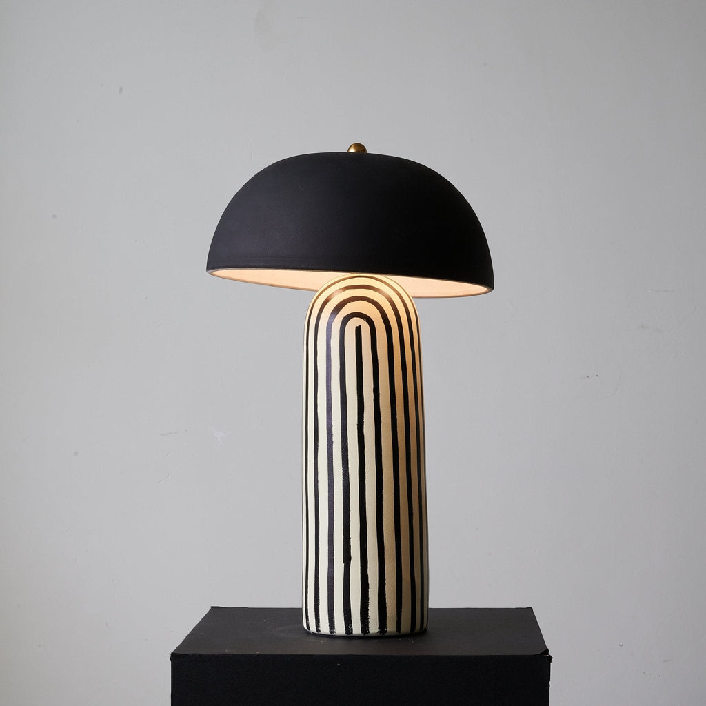 Turned slightly to one side on its black plinth, this Clérachic table lamp shows the black-and-white striping curve around the base.