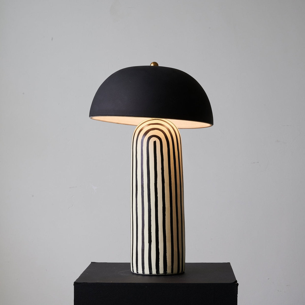 Turned slightly to one side on its black plinth, this Clérachic table lamp shows the black-and-white striping curve around the base.