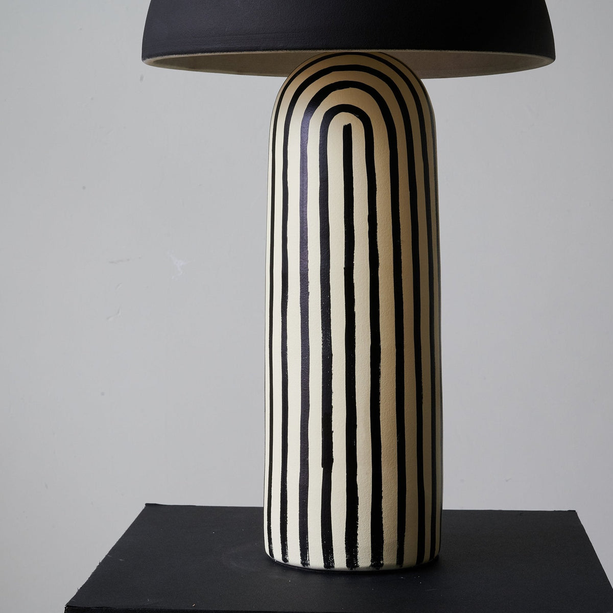 A low angle looks up at this Clérachic table lamp's striped ceramic base toward the underside of the dome shade.