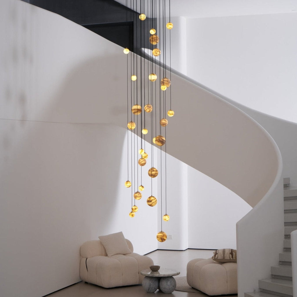 Daylight view with the lit chandelier centred in the stairwell, its spiral set against white plaster.