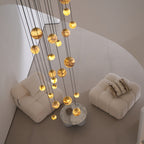 Angled overhead daylight view of the lit globes descending toward a marble table between two armchairs.