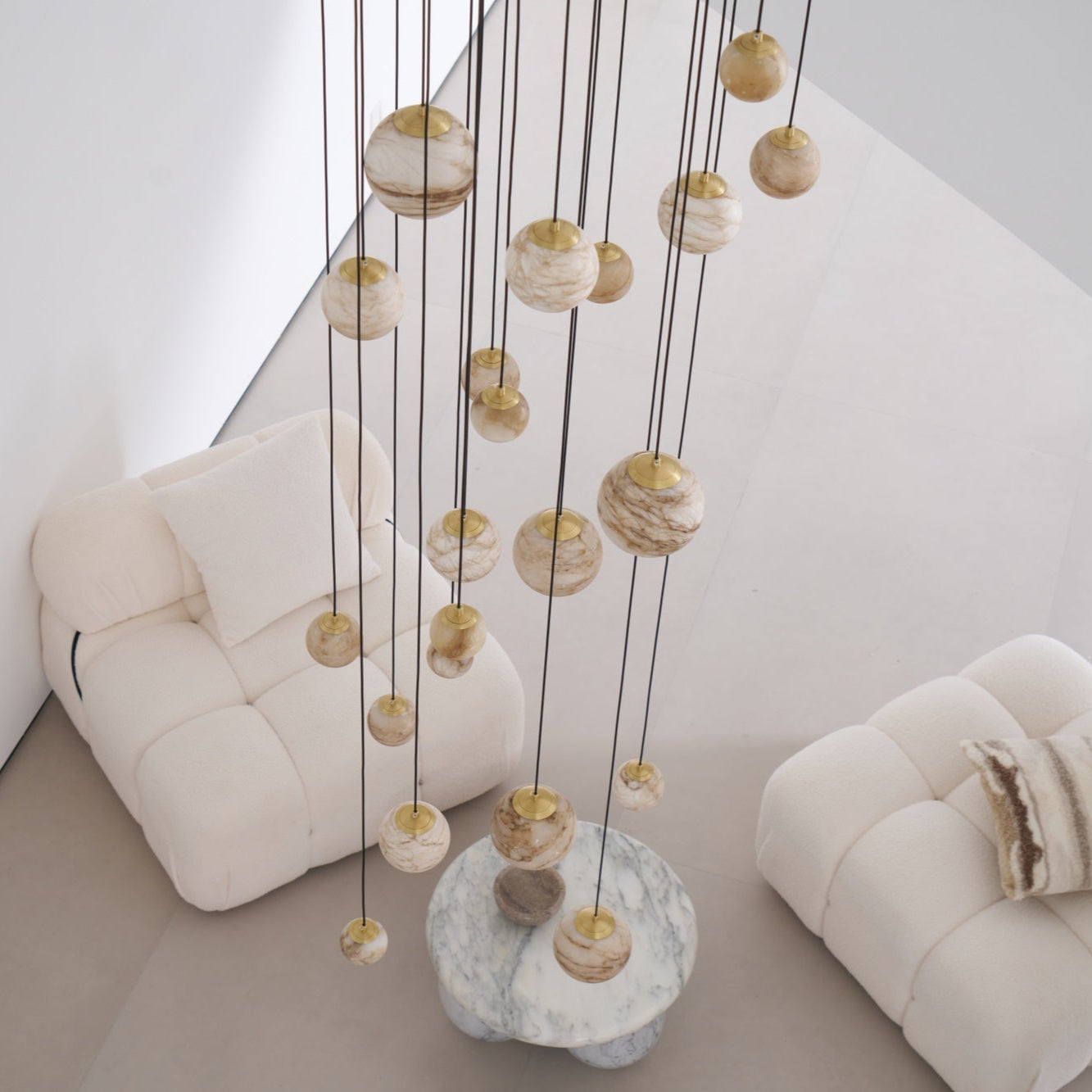 Overhead angle on the unlit globes, brass caps and cream alabaster above a round marble table.
