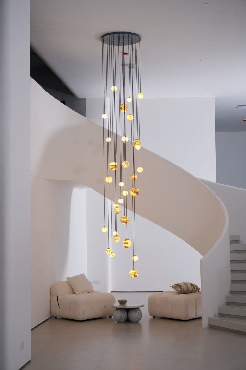 The warm cascade seen past a white pillar, dropping alongside the curving ribbon of the staircase.