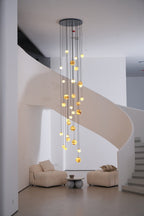 The warm cascade seen past a white pillar, dropping alongside the curving ribbon of the staircase.