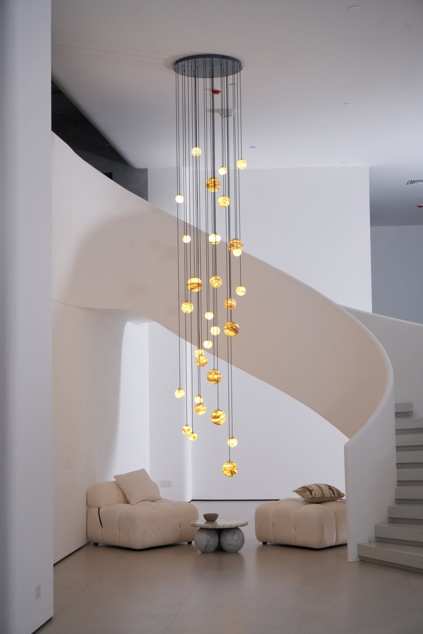 The warm cascade seen past a white pillar, dropping alongside the curving ribbon of the staircase.