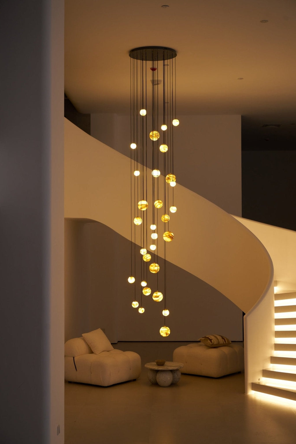 The Sultana chandelier at dusk, globes glowing amber as the stair treads light up behind it.