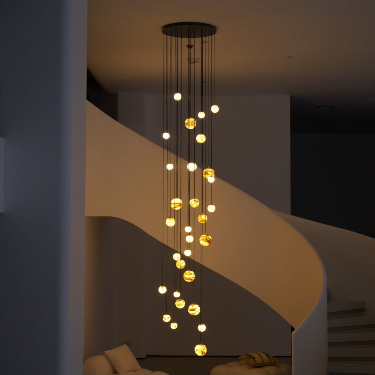 After dark the chandelier reads as a slow spiral of amber points against the shadowed stair wall.