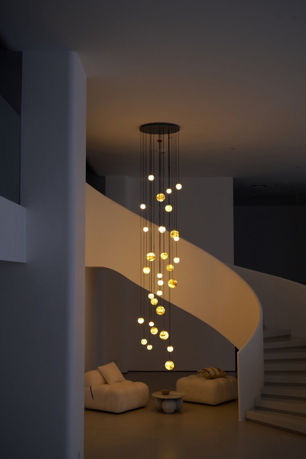 Night view from across the room, the lit globes suspended in an otherwise dark double-height space.