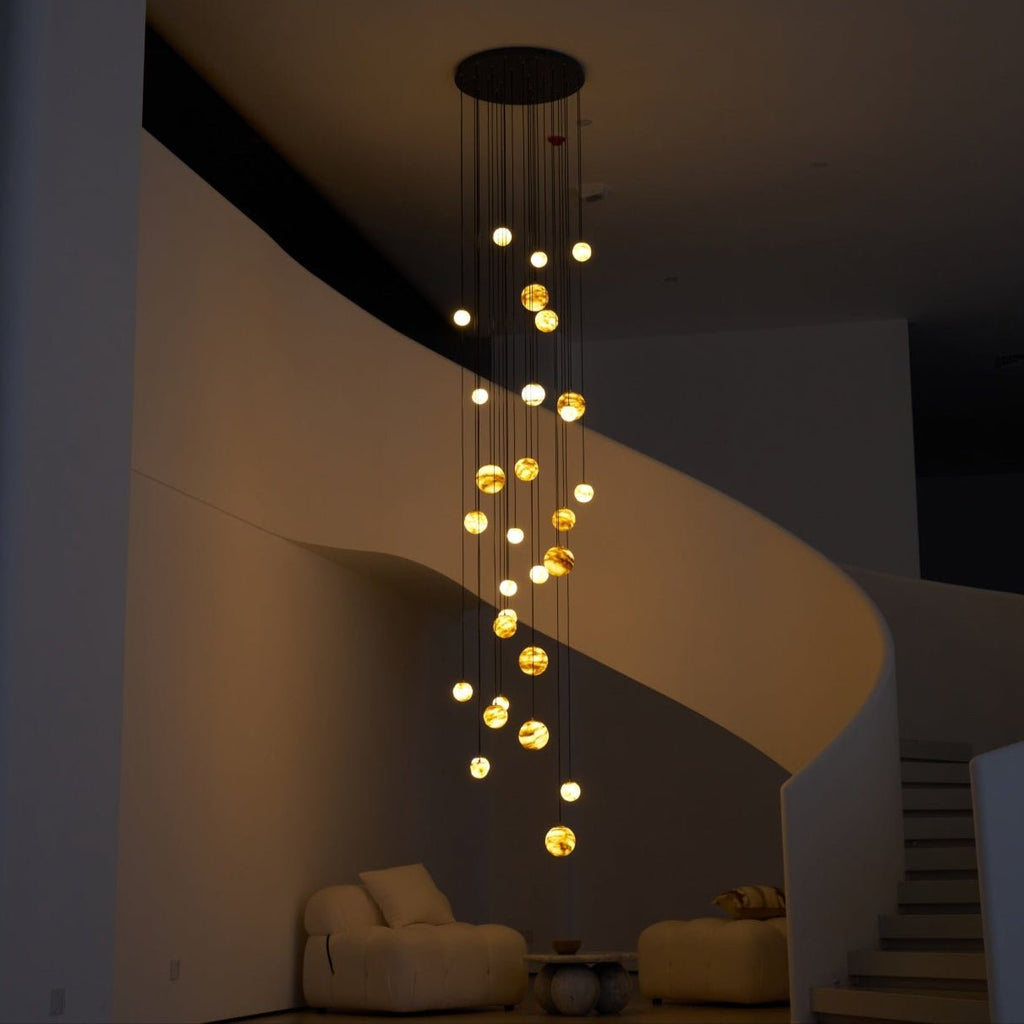 The lit cascade at night, washing soft light across the curved plaster wall of the stairwell.