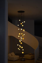 The chandelier lit in a dim room, its globes marking the full drop from ceiling plate to seat height.