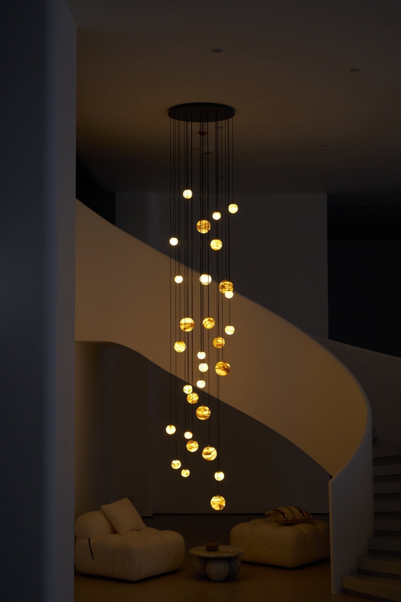 The chandelier lit in a dim room, its globes marking the full drop from ceiling plate to seat height.