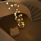 Looking down on the lit chandelier at night, the spiral stair treads curving away to the right.