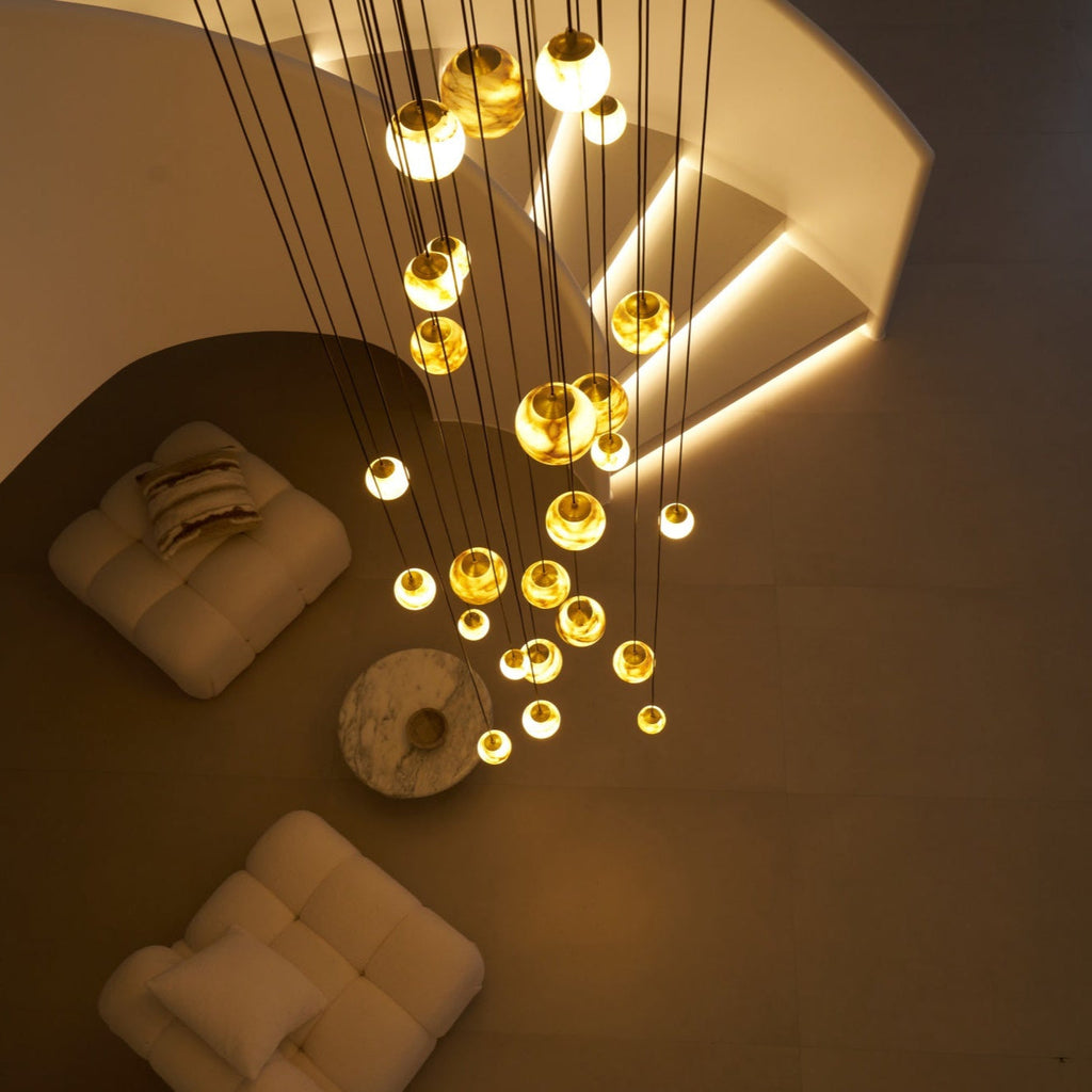 Top-down night view over the lounge, the stair's recessed strip lighting glowing behind the globes.