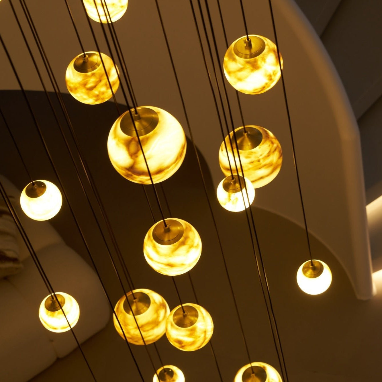 Close-up from below of the lit globes, showing the brass caps and cloudy veining inside the alabaster.