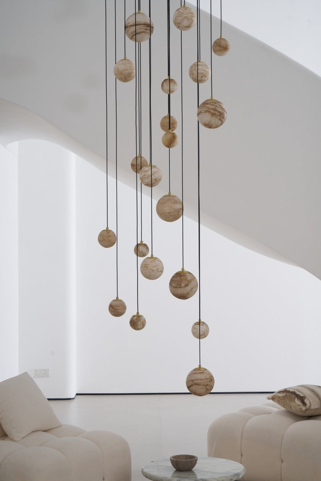 Closer daylight crop of the unlit globes, each hung on its own thin cable at a different length.