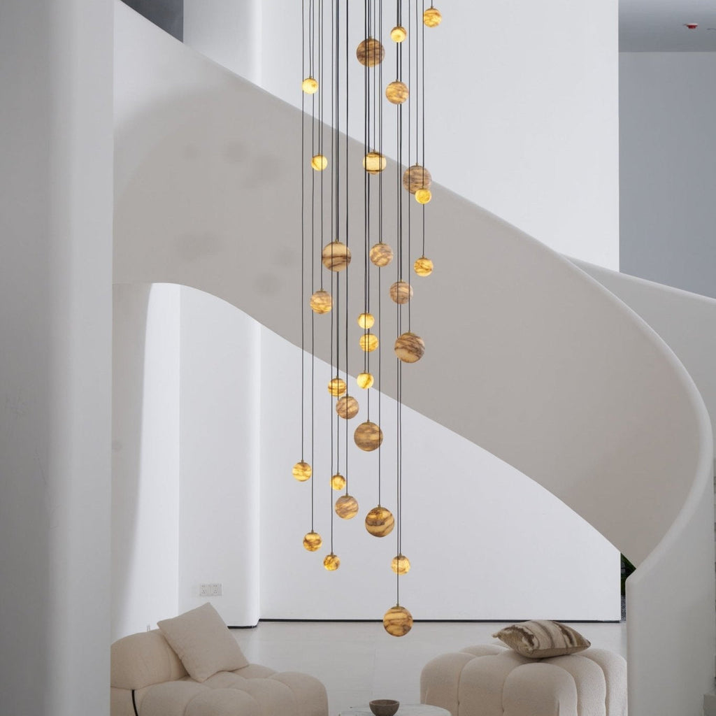 The lit Sultana chandelier from the side, globes staggered across the width of the stairwell.