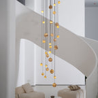 The lit Sultana chandelier from the side, globes staggered across the width of the stairwell.