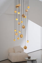 Portrait crop of the lit lower globes hanging just above a cream boucle armchair and marble table.