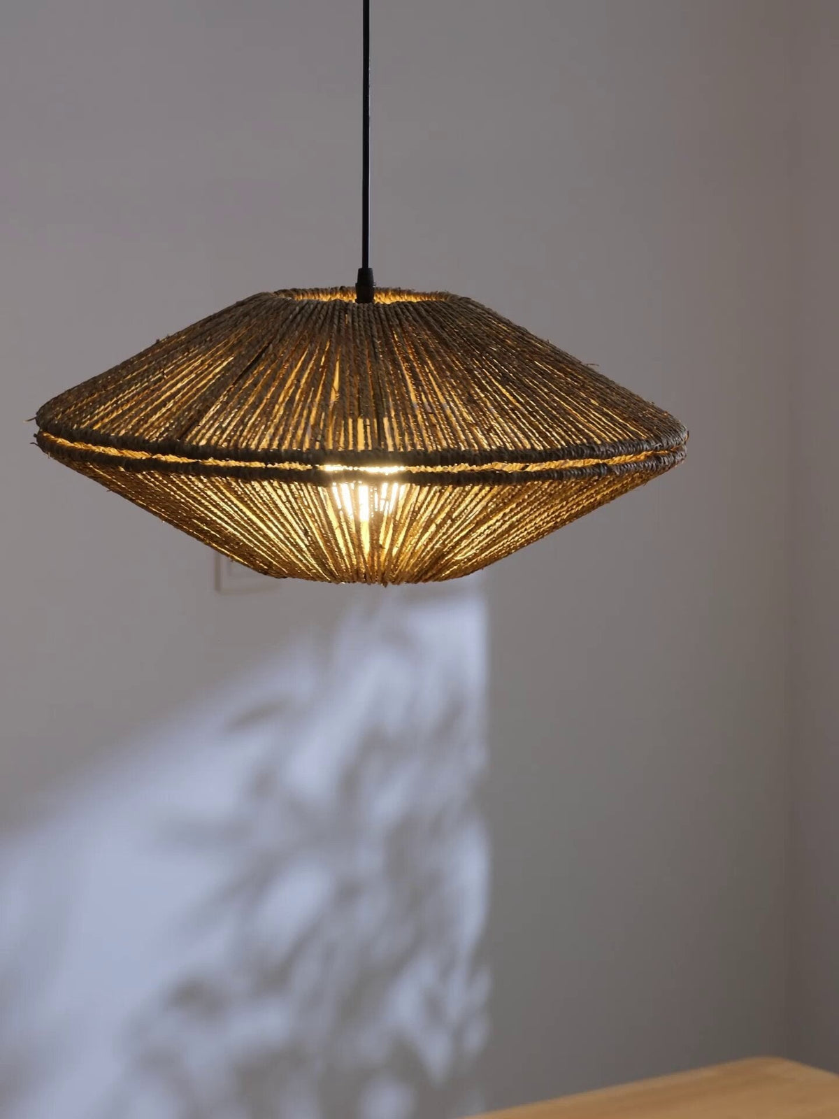 Lit against a plain grey wall, this Clérachic pendant throws a radiating shadow pattern across the surface behind it.
